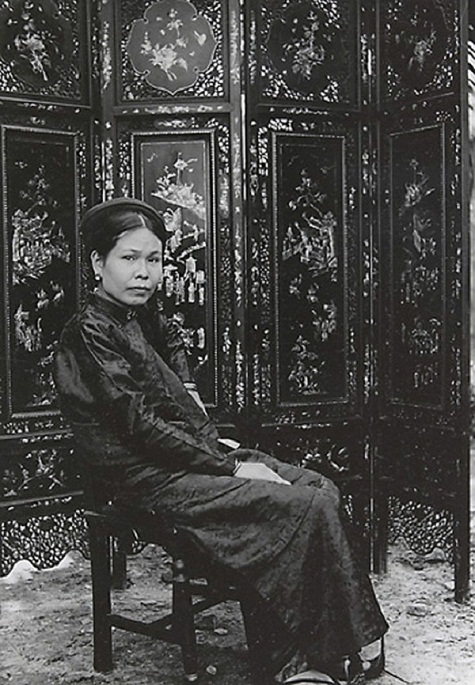 Một người phụ nữ quý tộc trung niên đang ngồi trong nhà mình.